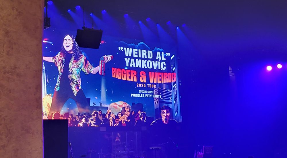 Stage of the Weird Al show with an image of Weird Al with the tour name Bigger & Weirder 