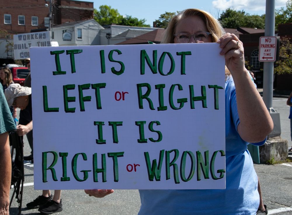 Woman holding a protest sign that reads 