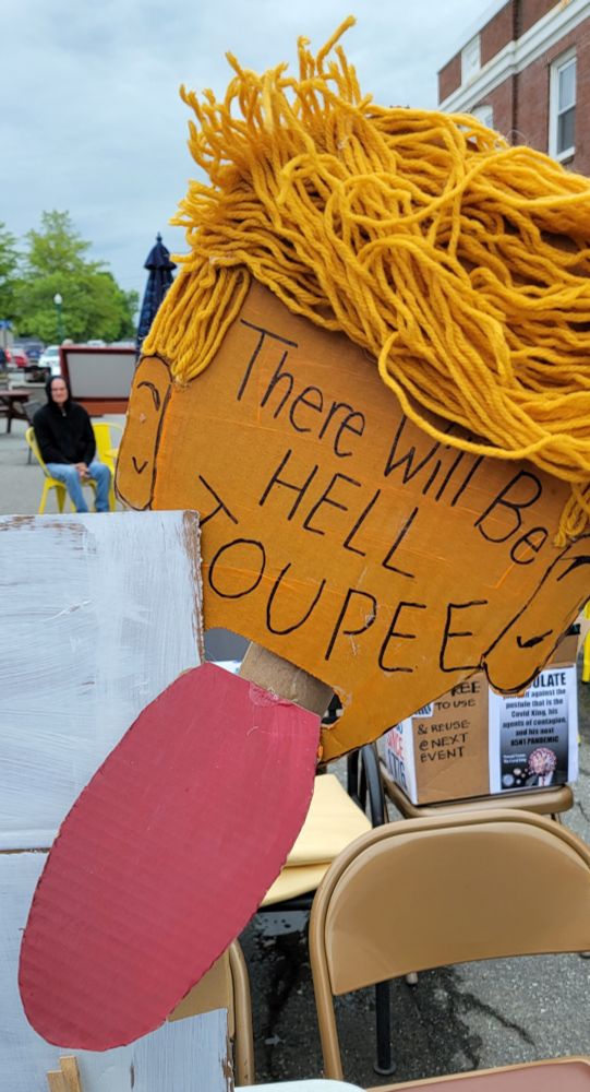 Yellow head with yarn for a bad toupee and a large pink tongue. Text "There will be hell toupee."