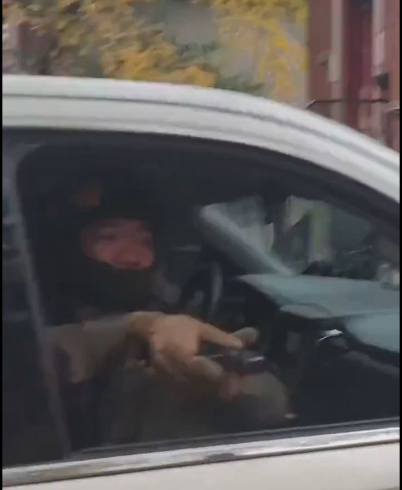 Supposedly a federal agent with a handgun held fully horizontal pointing out a car window. 