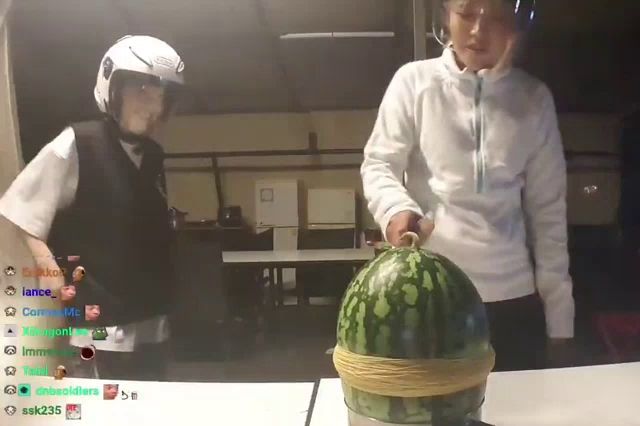 a man wearing a white helmet stands next to a watermelon