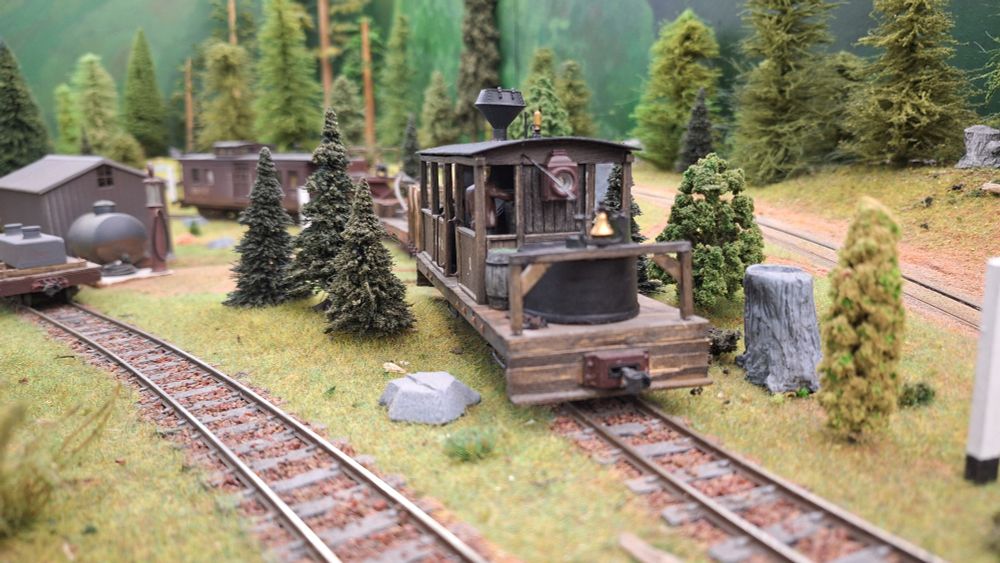 A Dunkirk class locomotive leads a maintenance train through a curve with tracks sloping up to the right and down to the left.