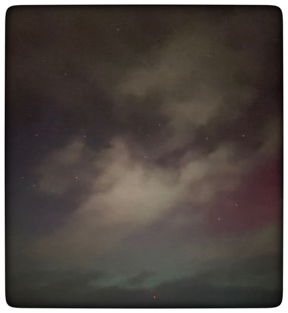 Picture of the night sky with light cloud and coloured with pink and greenish blue aurora light.  