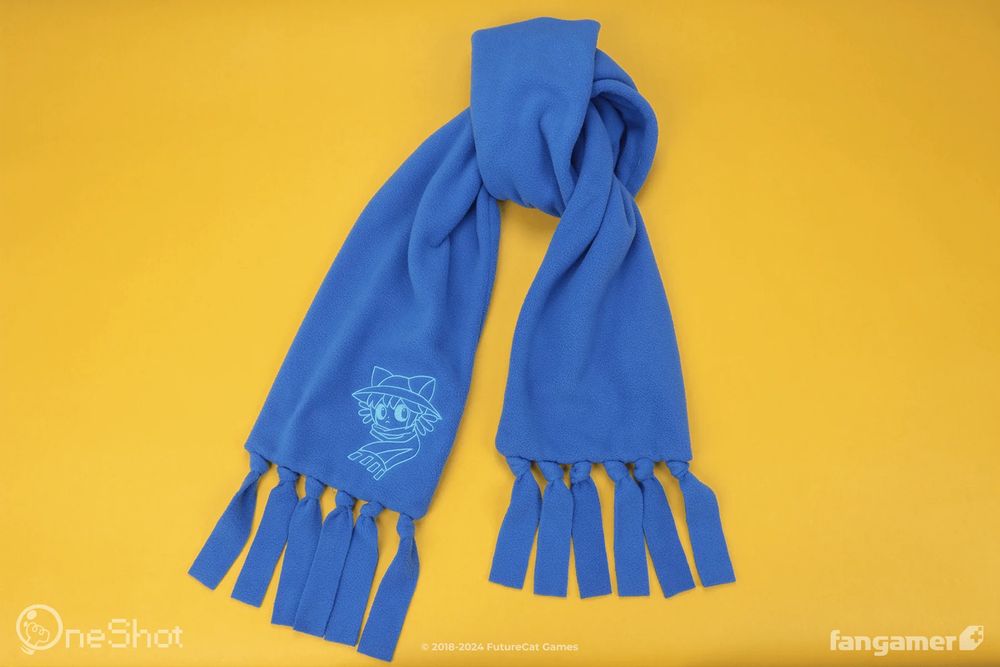 A long blue, tasseled scarf with an embroidered Niko design on one end. 