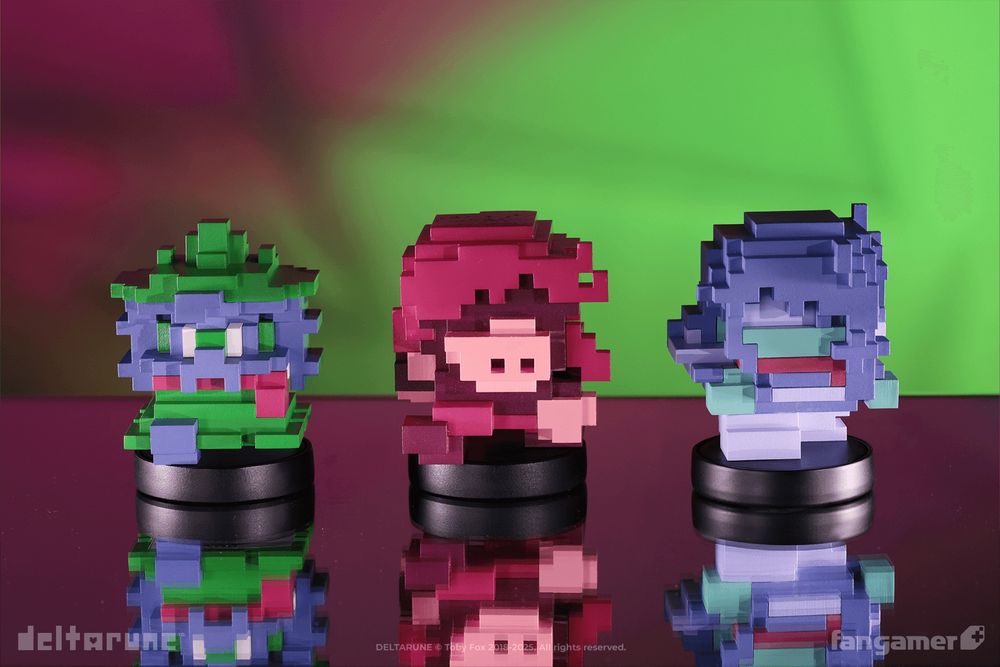 A photograph of the upcoming HERO_SCARF, HERO_AXE, and HERO_SWORD voxel-style figurines against a green and red background. 