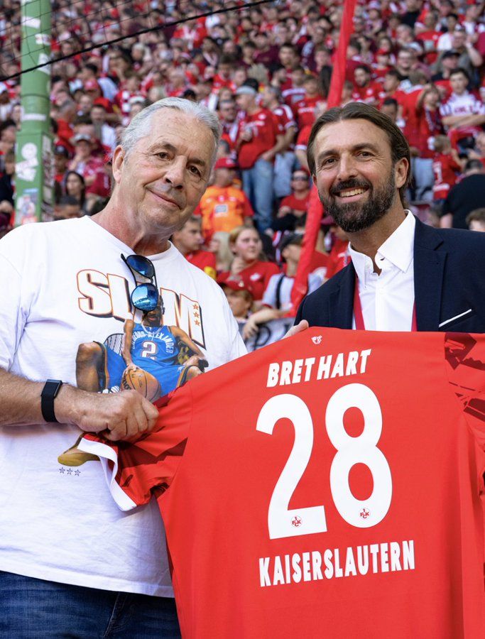 Wrestling legend Bret Hart wears a Shai Gilgeous-Alexander shirt while presented with a custom jersey from the Kaiserslautern football club