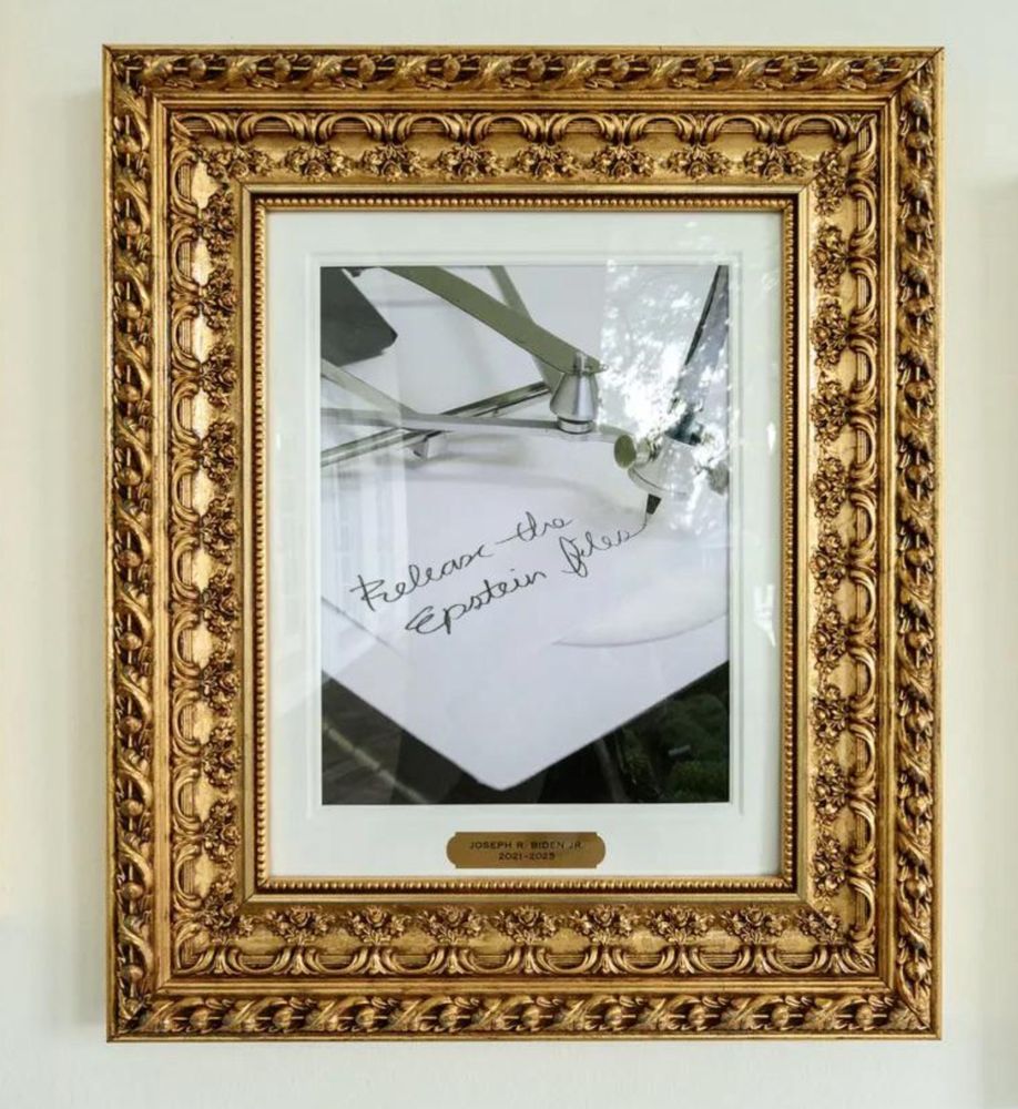 Framed image of Joe Biden’s auto pen writing, “Release the Epstein Files” hanging among presidential photos.