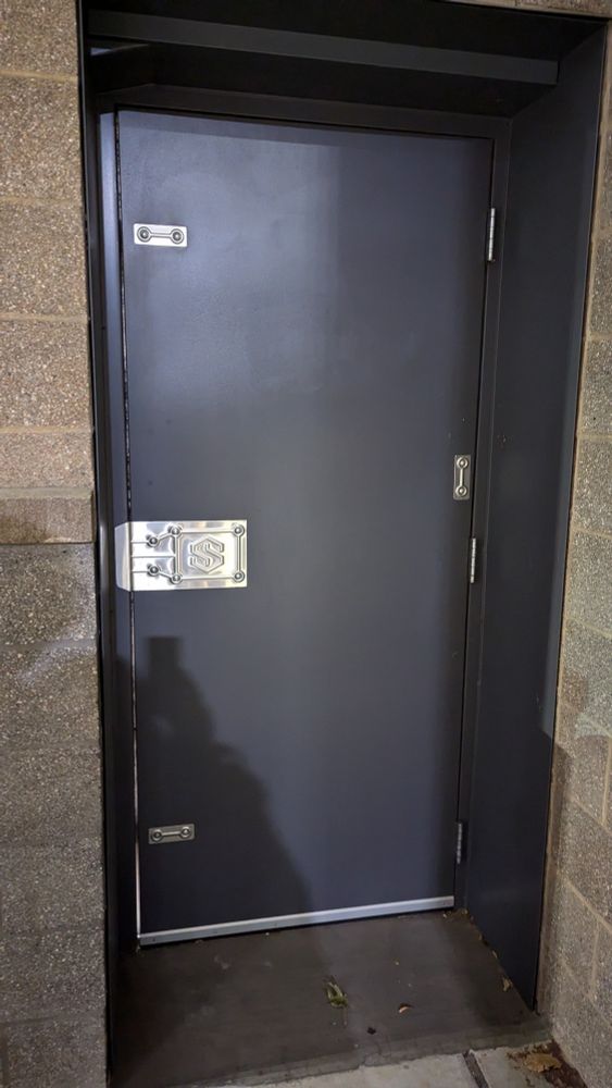 A nondescript blue door with a super s stamped on a polished steel plate where the handle would be.