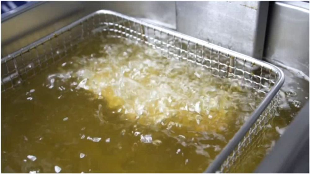 a stainless steel fryer is filled with a yellow liquid