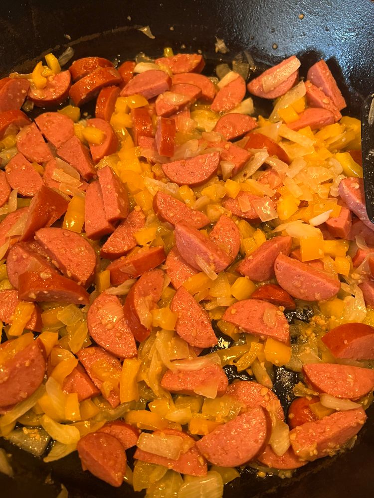 A picture of a cast iron skillet with onion, yellow bell pepper, Hillshire Farms smoked sausage, and minced garlic from a jar all cooking in it on the stove. I sweated the onion for at least a good 20 to 30 minutes, then added the bell pepper for another 10 minutes or so before adding the cut up sausage and garlic. Just basically waiting on the sausage to get nice and brown, and I’m contemplating turning it into a really big frittata.