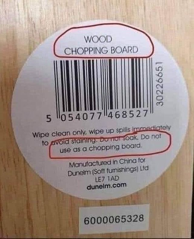 Die Unterseite eines Holzbretts zeigt einen Aufkleber mit Strichcode auf dem steht: wood chopping board, und darunter als Anweisung: wipe clean only, wipe up spills immediately to avoid staining. do not soak, do not use as a chopping board. manufactured in China. 