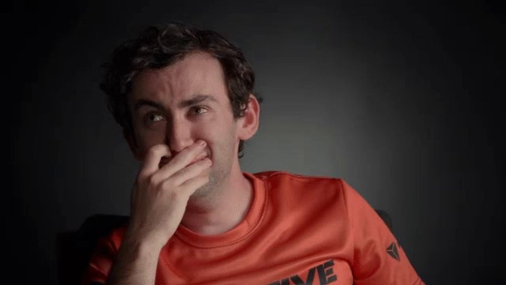 a man wearing an orange shirt with the word five on it covering his mouth