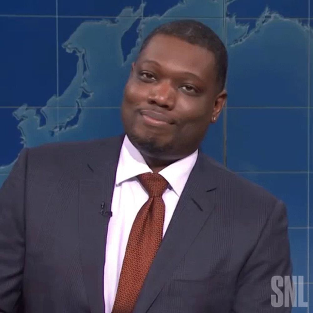 a man in a suit and tie is smiling in front of a snl logo