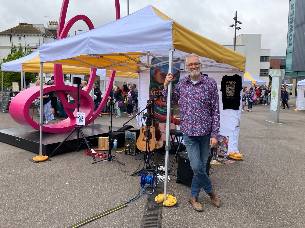 Gazebo full of band set up with Jim standing posing at the front