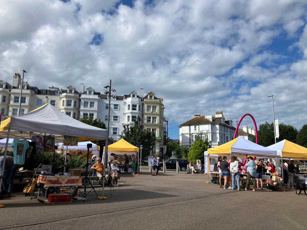 Market stalls under a blue and grey sky, people browsing