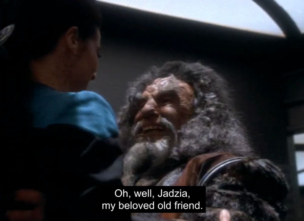A screenshot from Star Trek Deep Space Nine of a Klingon named Kor embracing Jadzia Dax, saying, "Oh, well, Jadzia, my beloved old friend"