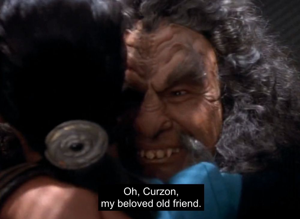 A screenshot from Star Trek Deep Space Nine of a Klingon named Kor hugging Jadzia Dax, saying, "Oh, Curzon, my beloved old friend"