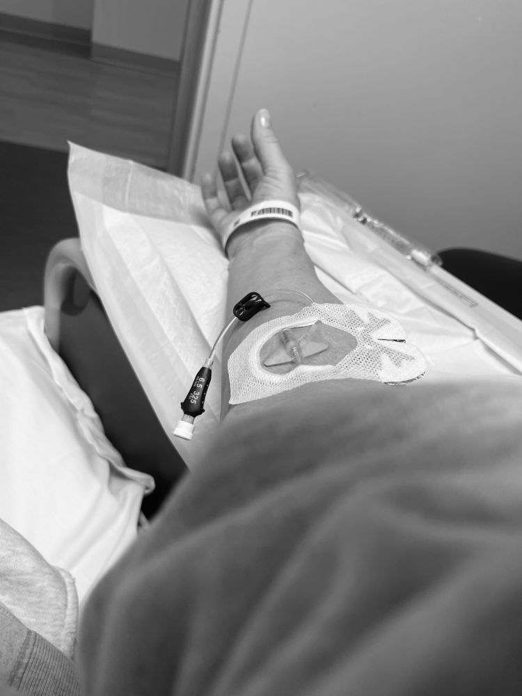 A woman’s are extended out from blankets receiving immunotherapy treatment   She beat cancer 💛