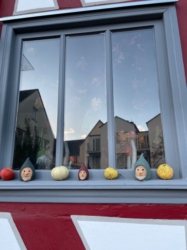Small heads of gnomes alternating with small squashes in a window at Lindburg an der Lahn Germany 