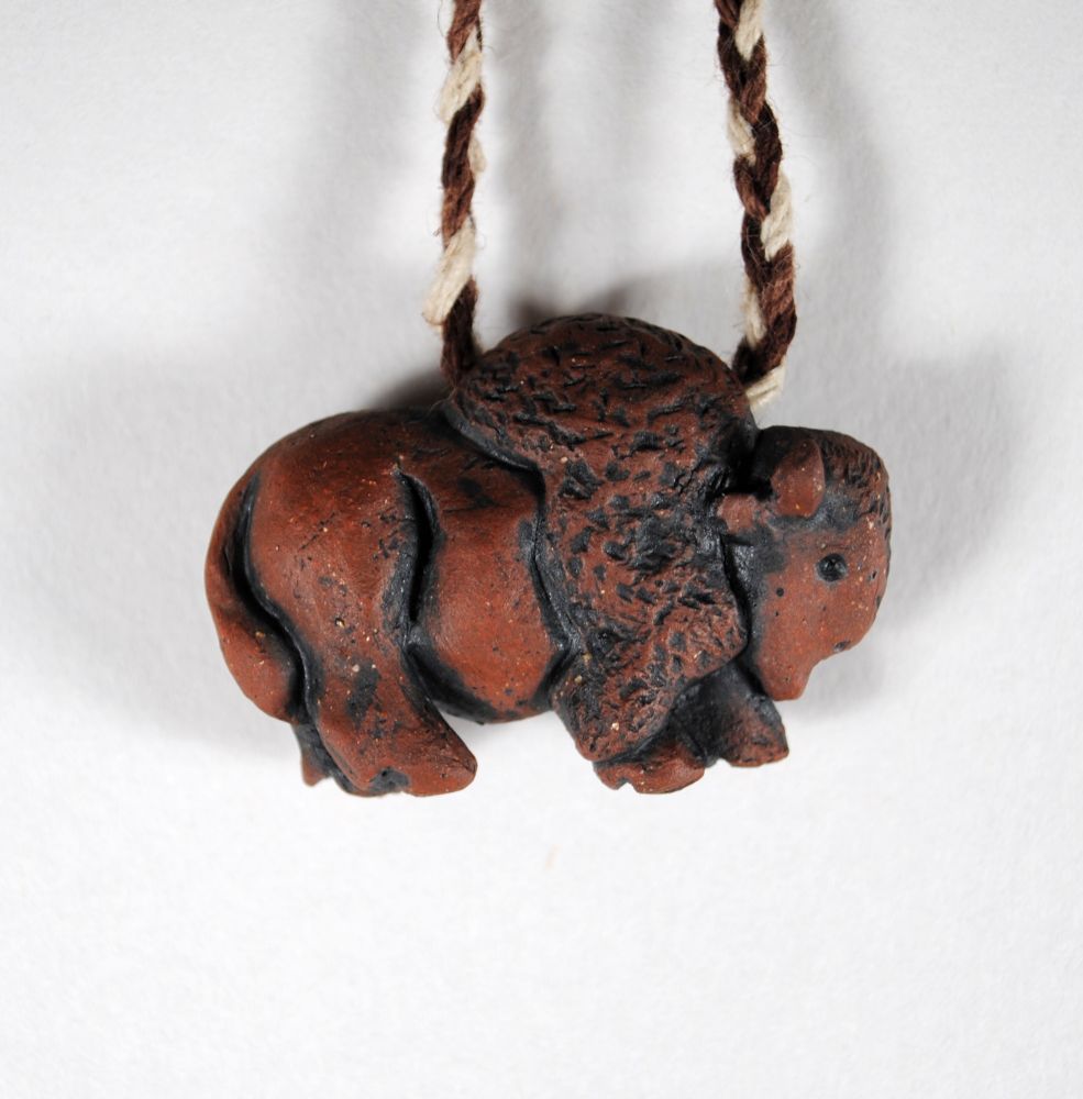 image of a red clay bison pendant suspended by a necklace cord, left side