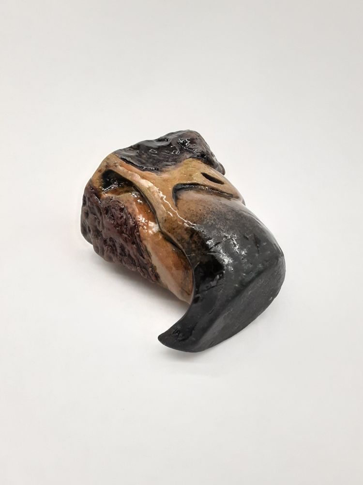 white background photo of a ceramic shot glass in the shape of an eagle beak. 