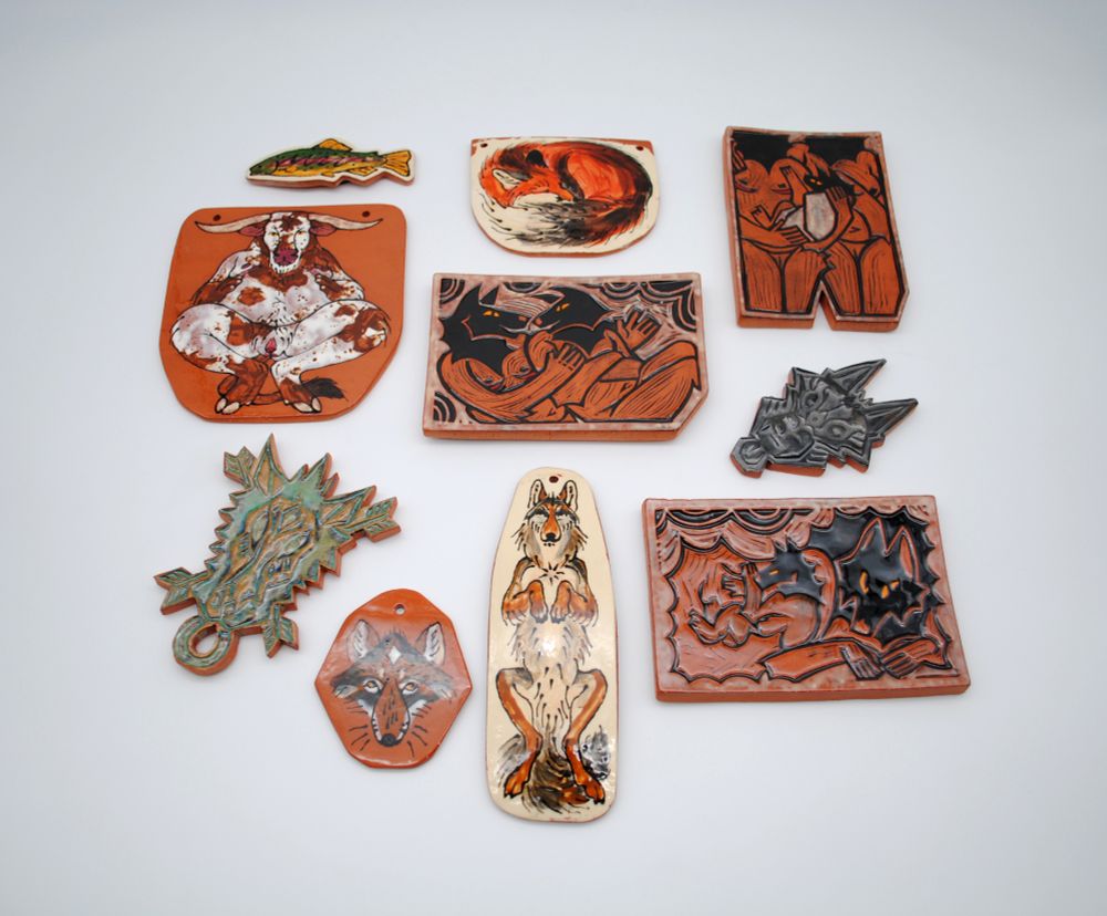 photo featuring a variety of ceramic tiles made for hanging on the wall featuring various animals and some transgender animal figures. the fish is a magnet!