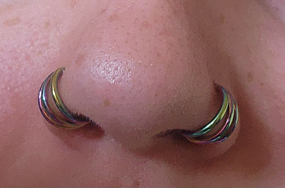 Double nostril piercing with double rainbow triple rings