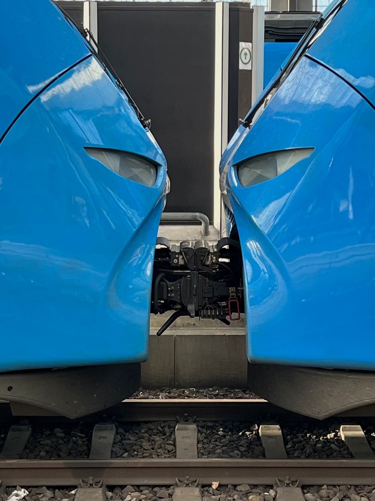 The meeting point of two train cars in the Munich train station with headlights that seem line up like silhouetted faces.