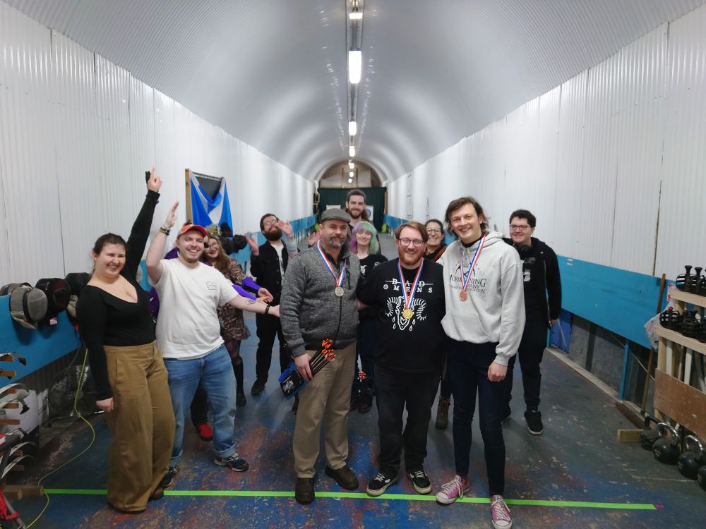 The three medalists of the archery tournament standing in front of the other participants 
