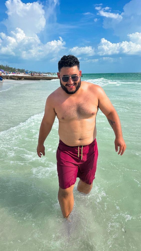 Hispanic guy walking through water on a Florida beach
