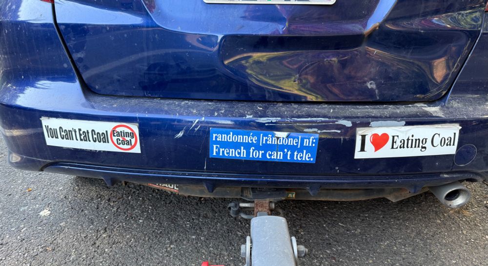 three bumpers stickers on a car. “you can’t eat coal”, “randonnee: french for can’t tele” and “i heart eating coal”