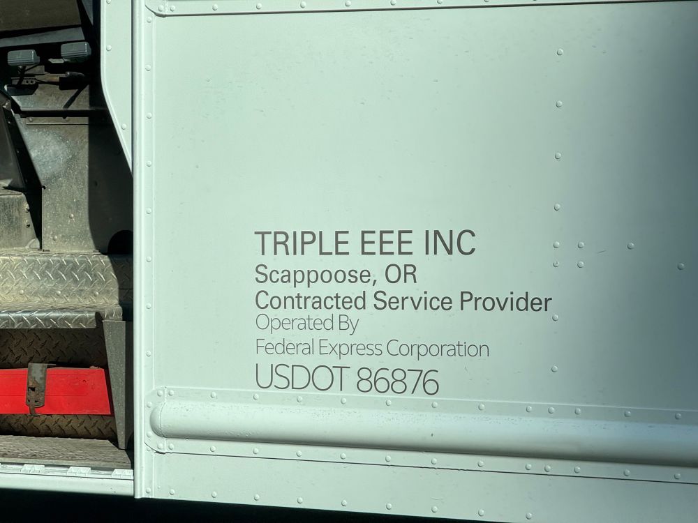 a fedex truck with a sign on the side saying it is operated by “triple eee inc.”