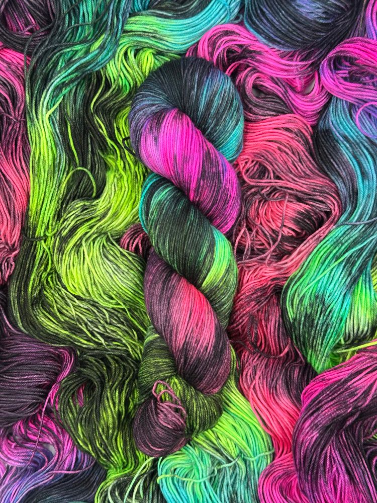 A twisted Hank of neon and black yarn on a bed of untwisted hanks in the same color 