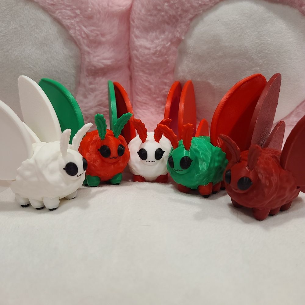 A collection of little moth friends I 3d modeled and printed, in a variety of red, green, and white, for the Christmas time.