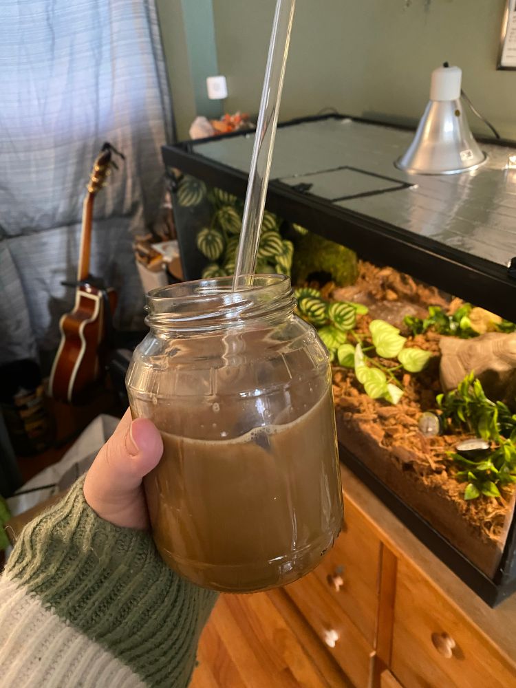 Applesauce jar filled with coffee and a long glass straw