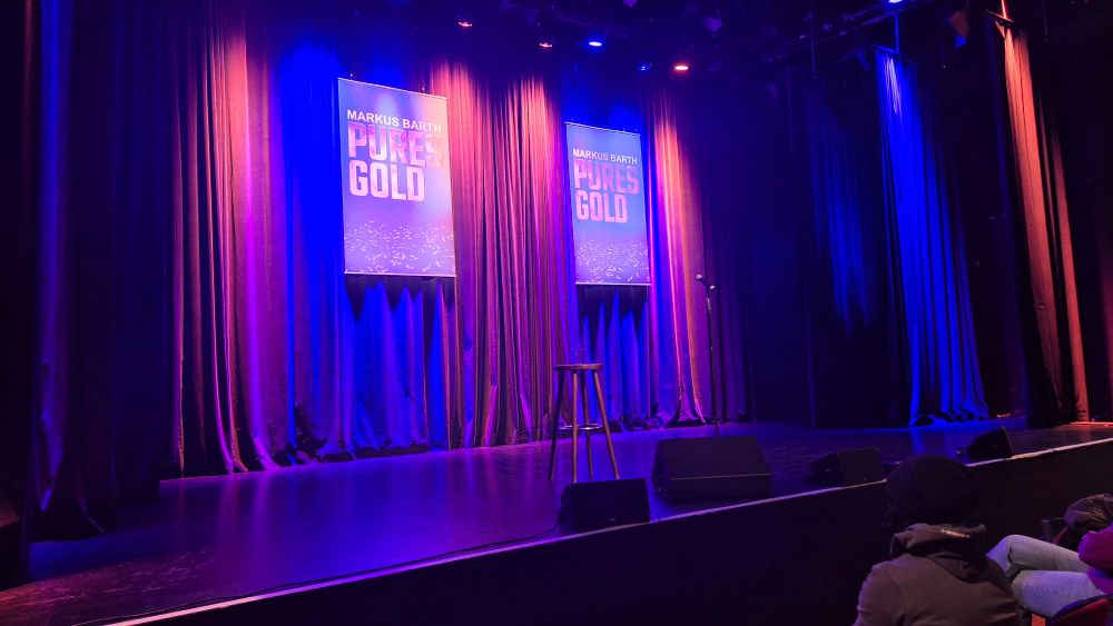 Eine Bühne mit 2 Schildern auf denen steht Markus Barth Pures Gold
