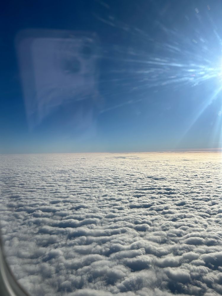 A picture of white clouds and the blue sky  from the window of an airplane 