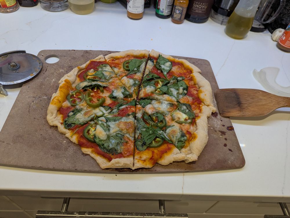 Homemade jalapeno and spinach pizza on a cutting board