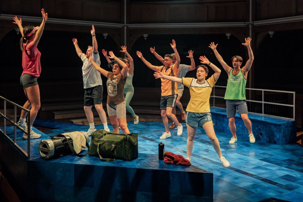 A group of people with their arms in the air and dressed in gym clothes. 