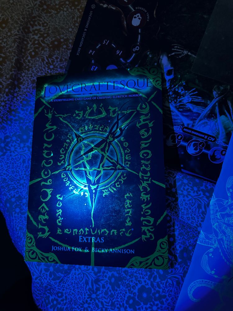 The secret art revealed on the extras book of Lovecraftesque 2e under UV torchlight. The torch reveals ethereal green mystic symbols on the black cover