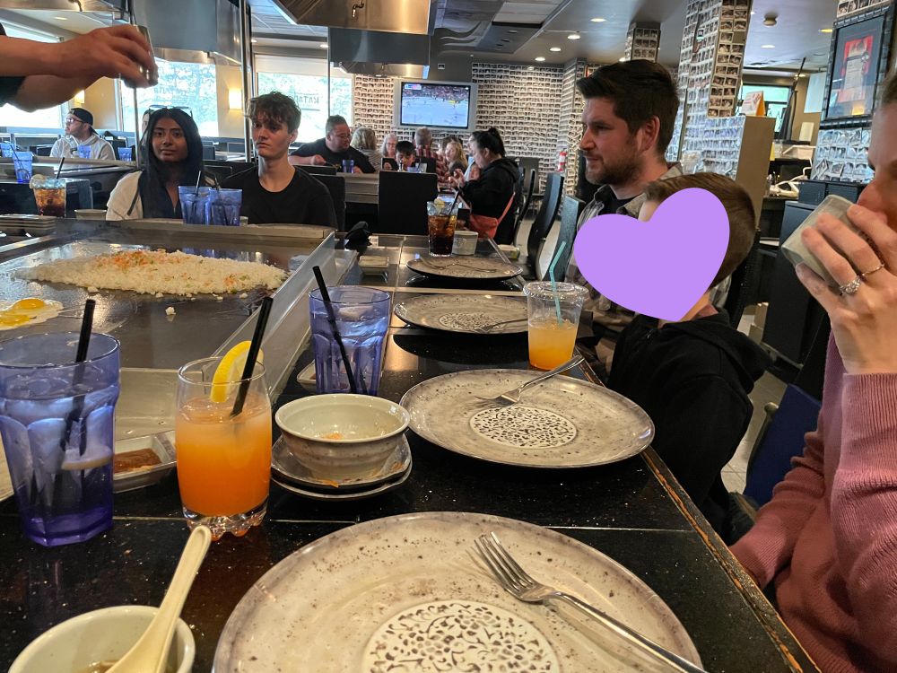 Matt, Colton, and Sarah sit watching the teppanyaki chef. 