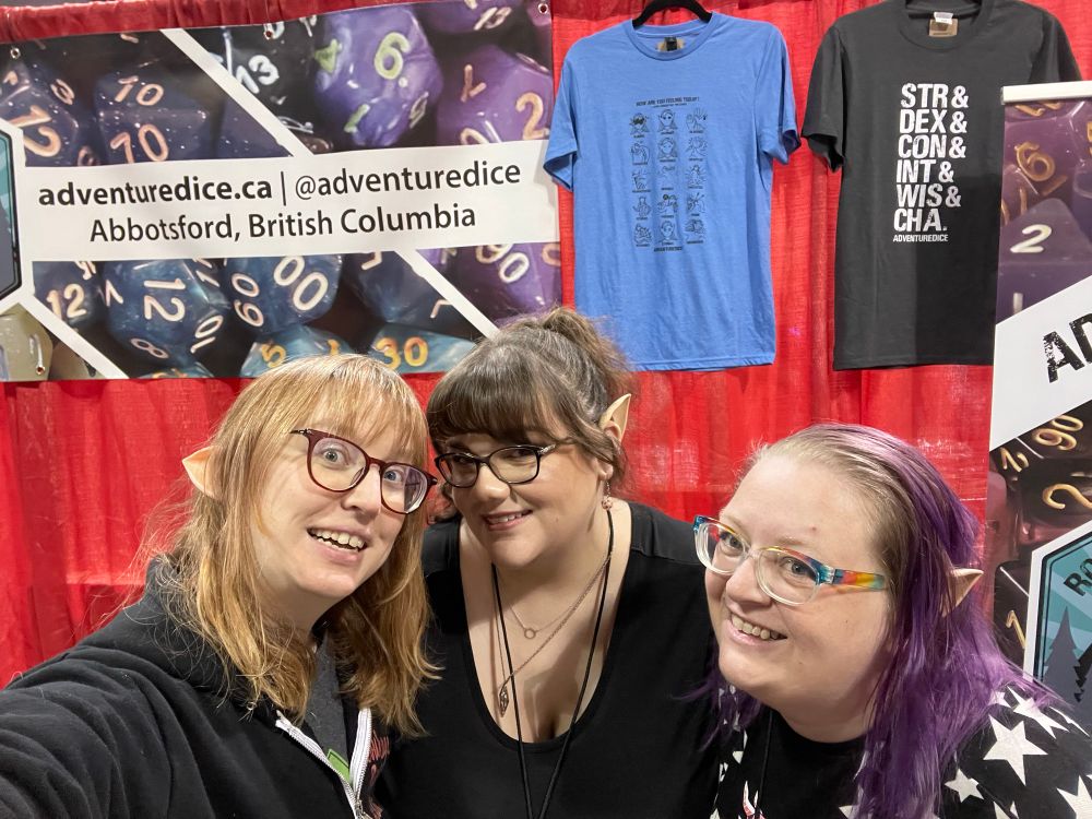 Three women stand together wearing wild ears, smiling at the camera at the Adventure Dice booth. 