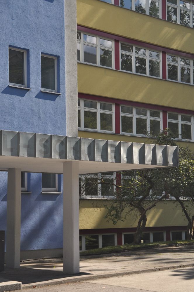 blaue schule mit blech-vordach. hinten weitere schulhaus in ocker