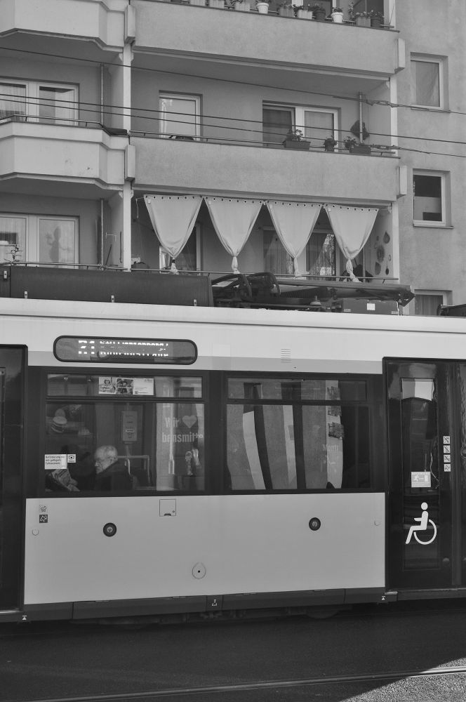 s/w. tram vor einem wohnhaus mit balkonen