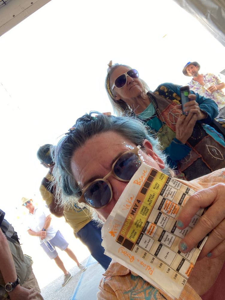 Woman with sunglasses on with Jazzfest schedule in front of face 