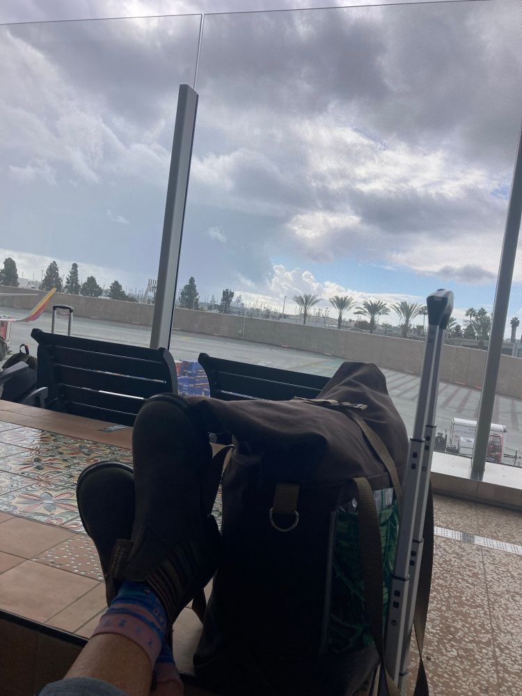 Person’s feet up with  boots on facing outdoor space in airport 