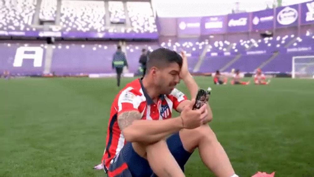 a soccer player is sitting on the field taking a picture of himself .