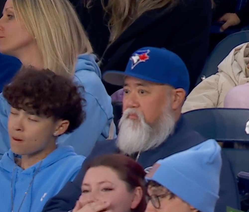 Paul Sun-Hyung Lee (Appa from Kim's Convenience) wearing a Blue Jays hat in the stands on Opening Day at the Blue Jays game in Toronto.