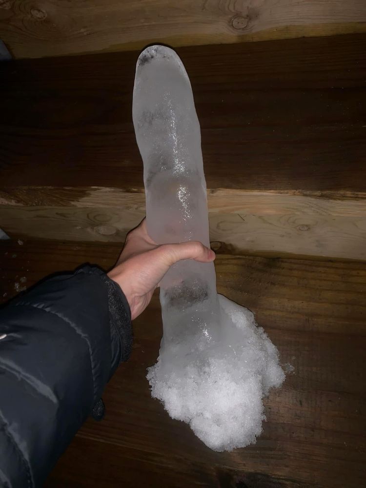 A hand holding a large detached icicle