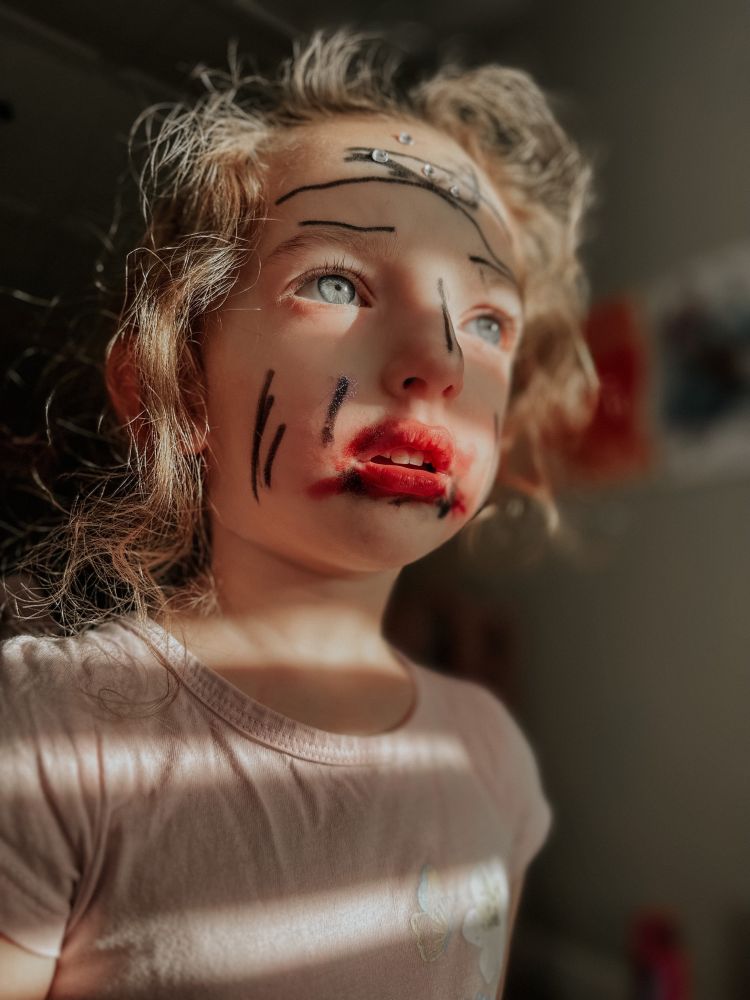 A perfect human child wearing elaborate makeup